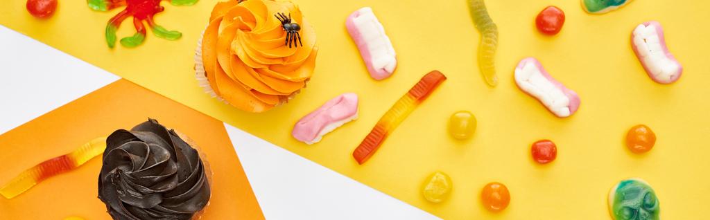 sarı ve beyaz arka plan üzerinde renkli sakızlı tatlılar ve cupcakes üst görünümü, Halloween tedavi - Fotoğraf, Görsel