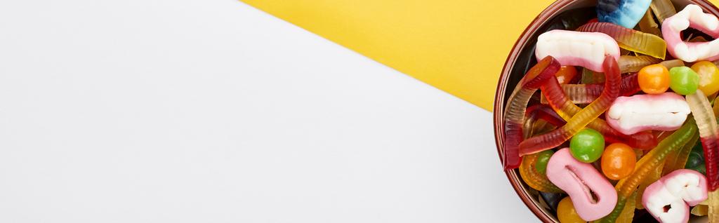 黄色と白の背景にボウルでカラフルなグミのお菓子のパノラマショット,ハロウィーンのお菓子 - 写真・画像