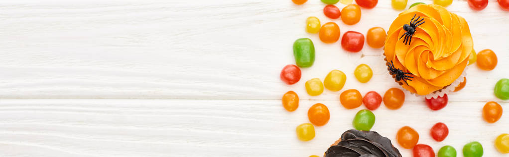 plano panorámico de coloridos bombones y cupcakes en la mesa de madera blanca, regalo de Halloween
 - Foto, Imagen