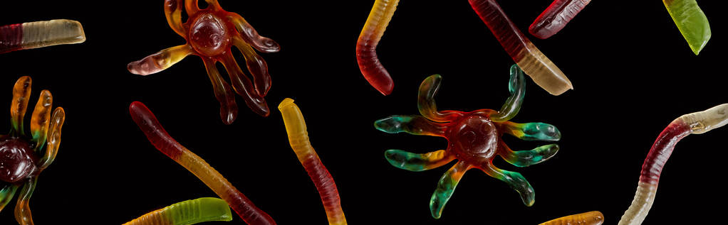 Top uitzicht van kleurrijke Gummy spinnen en wormen geïsoleerd op zwart, Halloween traktatie - Foto, afbeelding