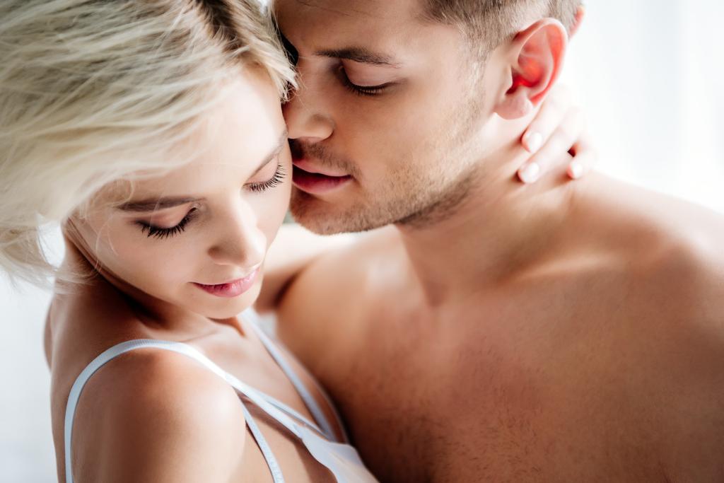 hombre guapo besándose atractiva y rubia mujer en ropa interior blanca
  - Foto, Imagen