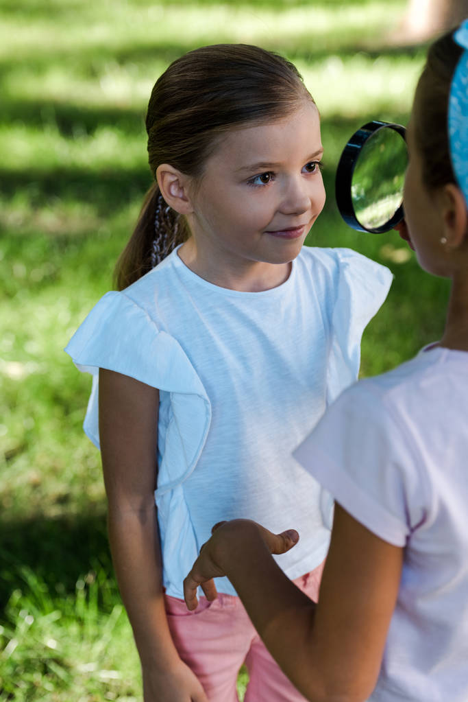 selective focus of kid holding magnifier near friend outside  - Photo, Image
