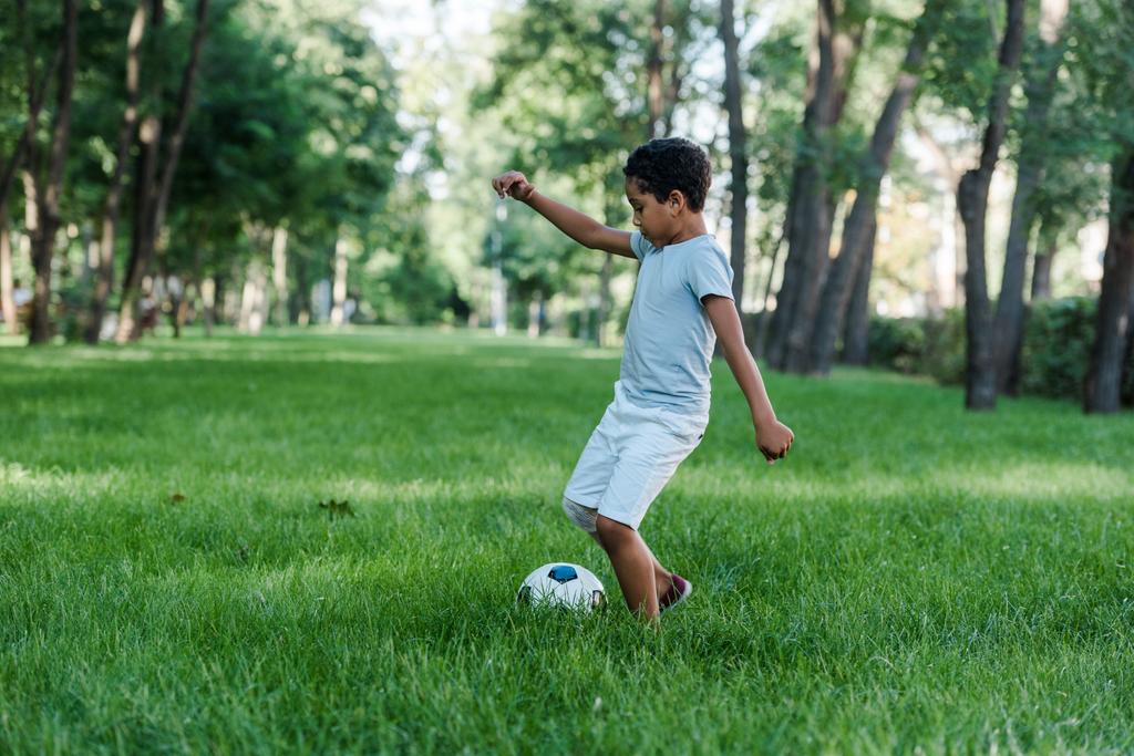 rozkošný africký americký kluk hraje fotbal na zelené trávě  - Fotografie, Obrázek