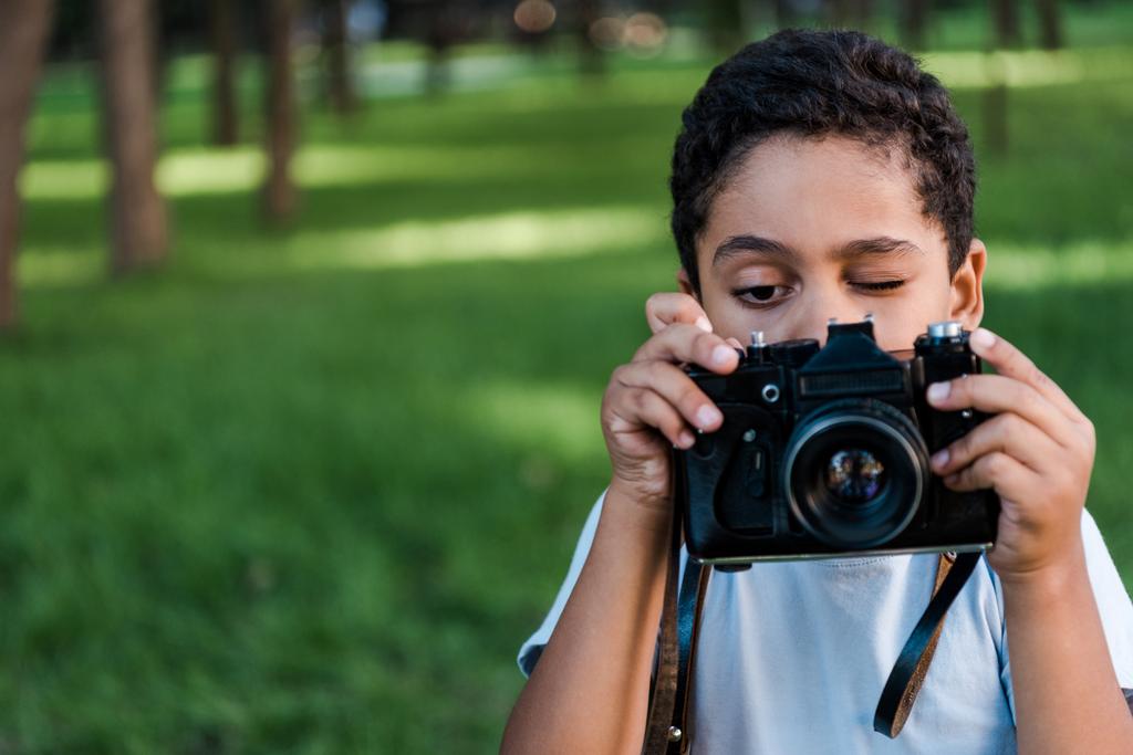 africký americký chlapec drží digitální fotoaparát při mluvení fotografie v parku  - Fotografie, Obrázek