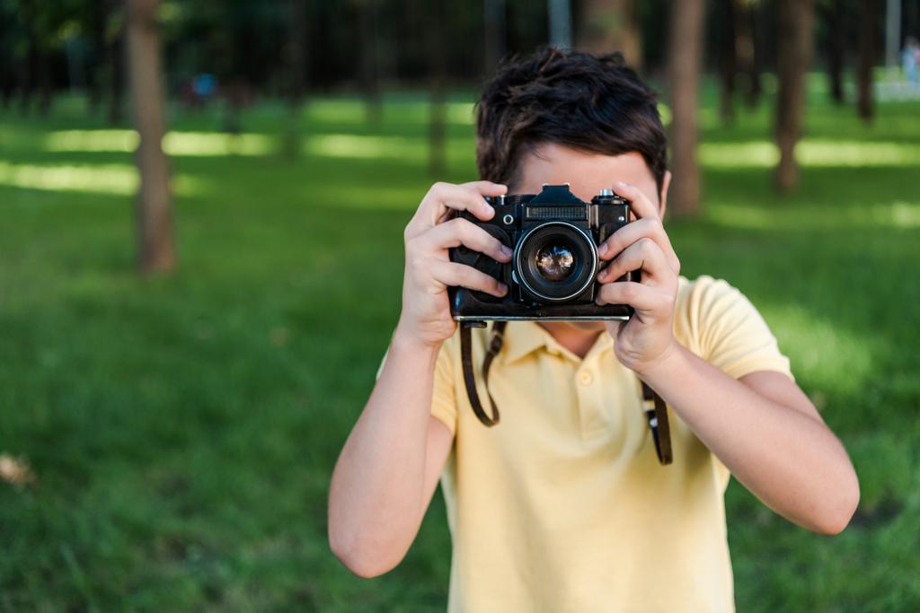 słodkie chłopiec gospodarstwa cyfrowe aparat podczas rozmowy zdjęcia w parku  - Zdjęcie, obraz