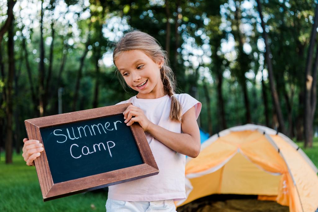 szczęśliwy dzieciak gospodarstwa tablicy kreda z letnich listów obozowych w parku - Zdjęcie, obraz