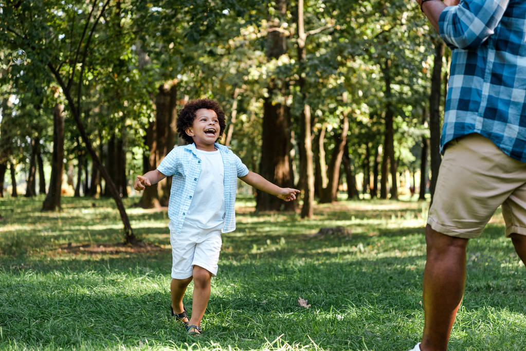 feliz afroamericano niño corriendo y mirando a padre
  - Foto, Imagen