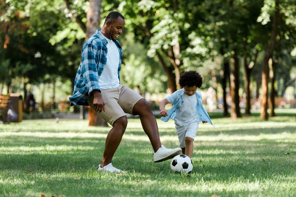feliz africano americano hombre jugando fútbol con rizado hijo
  - Foto, Imagen