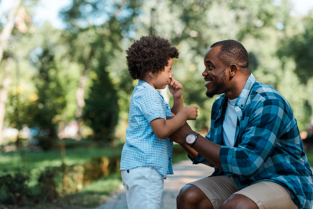 happy african american man looking at frustrated curly son  - Photo, Image