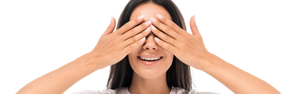 panoramiczne ujęcie szczęśliwej młodej kobiety zakrywającej oczy na białym  - Zdjęcie, obraz