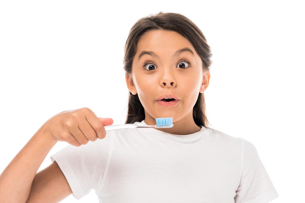 surprised kid looking at camera and holding toothbrush isolated on white  - 写真・画像