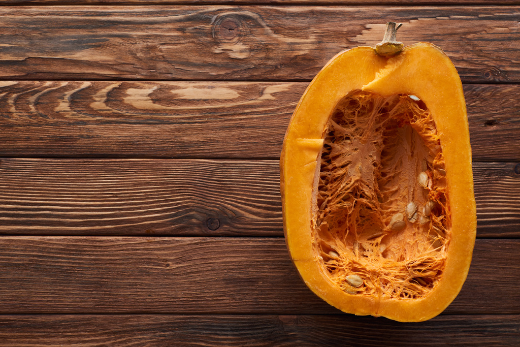 top view of ripe pumpkin half on brown wooden surface - Photo, Image