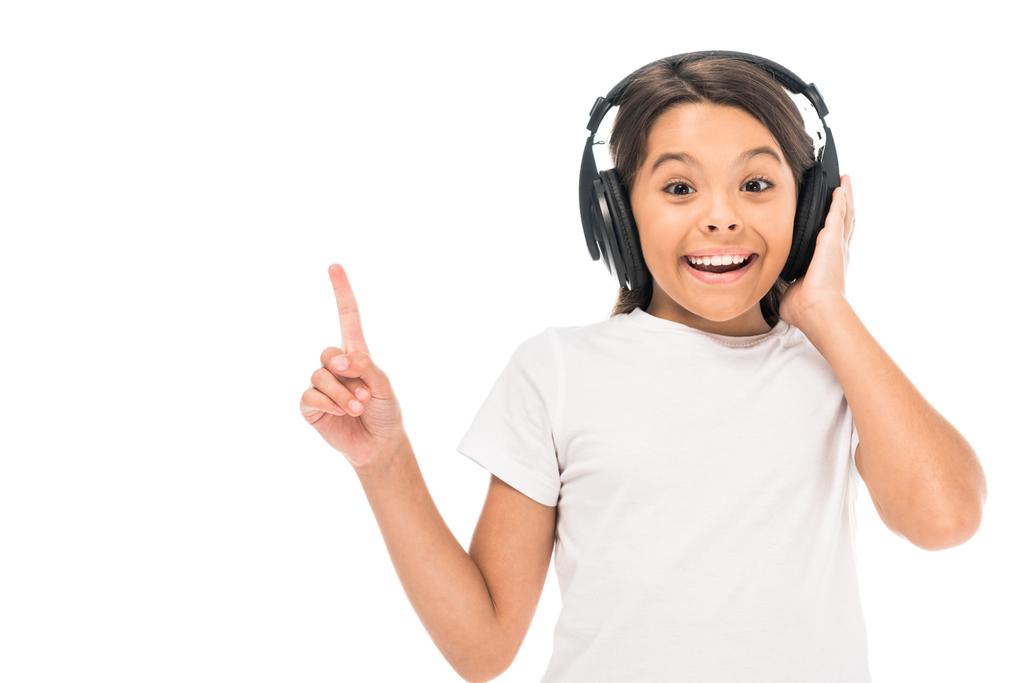 niño feliz escuchando música en auriculares y señalando con el dedo aislado en blanco
  - Foto, imagen