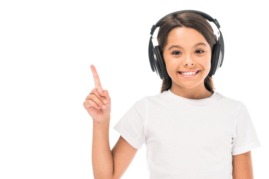 adorable kid listening music in headphones and pointing with finger isolated on white  - 写真・画像