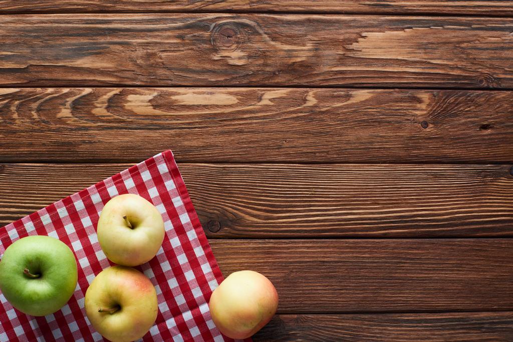 top view of checkered tablecloth with ripe apples on wooden surface with copy space - Photo, Image