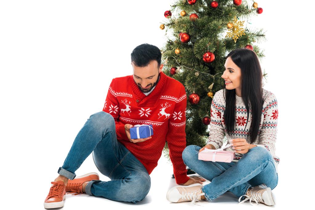 homem alegre e mulher segurando presentes perto da árvore de Natal isolado no branco
 - Foto, Imagem