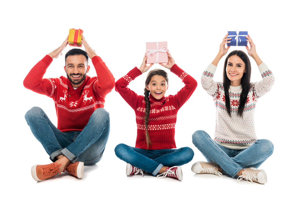 cheerful family in sweaters holding gifts above heads on white  - Photo, Image