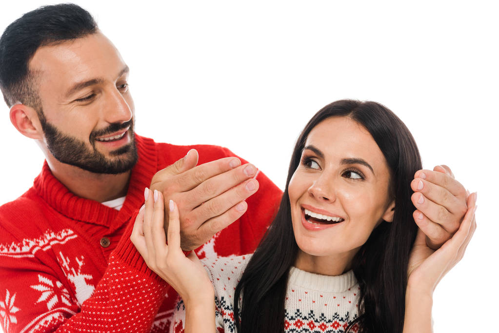 fröhlicher bärtiger Mann berührt Hände einer attraktiven Frau im Pullover isoliert auf weißem Grund  - Foto, Bild