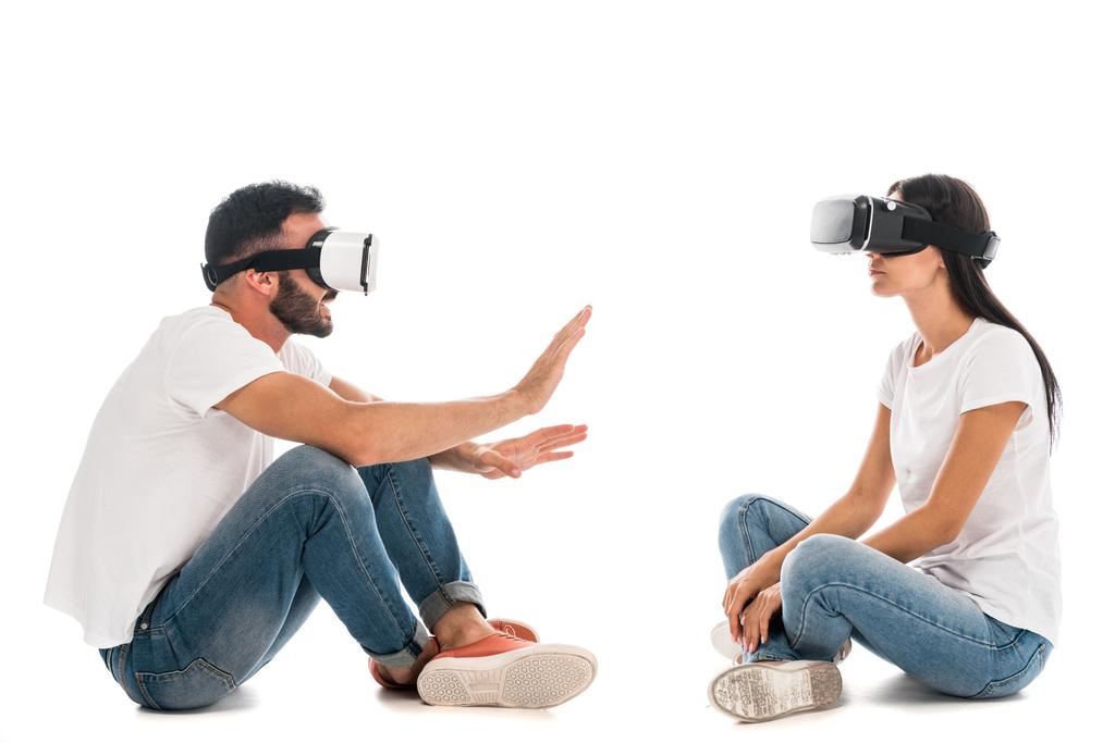 mężczyzna gestykulując blisko kobieta podczas korzystania z wirtualnej rzeczywistości zestaw słuchawkowy na biały  - Zdjęcie, obraz