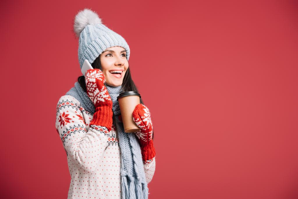 jolie femme en vêtements d'hiver parlant sur smartphone et tenant le café pour aller isolé sur rouge
 - Photo, image