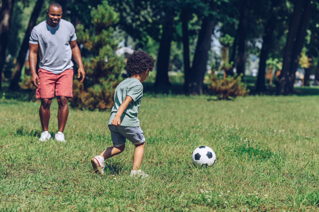 giovane padre afroamericano che gioca a calcio con il figlio carino nel parco
 - Foto, immagini