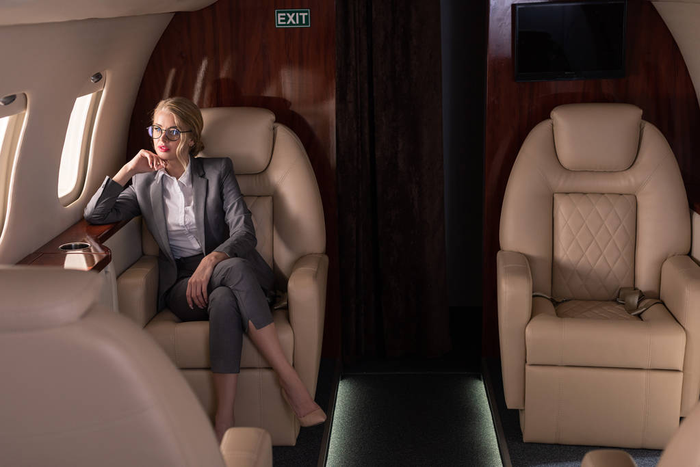 beautiful blonde businesswoman sitting in plane during business trip - 写真・画像