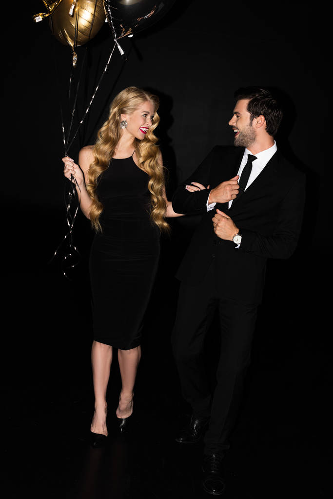 bella coppia allegra con palloncini d'oro sul partito isolato su nero
 - Foto, immagini