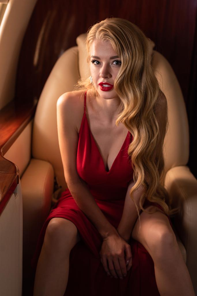 appassionato donna glamour in abito rosso seduto in aereo
 - Foto, immagini