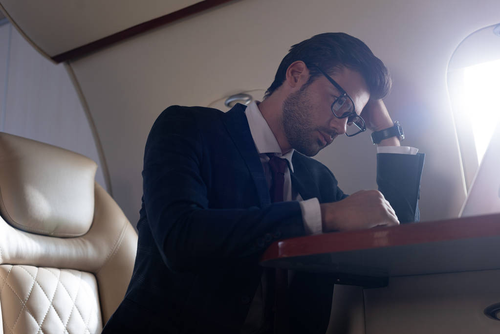 handsome tired businessman sitting in airplane during business trip  - 写真・画像