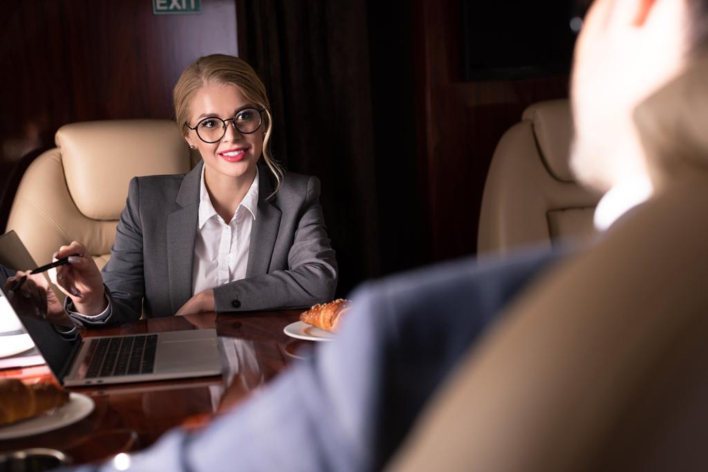 selective focus of professional businesspeople working with laptop in plane  - Photo, Image