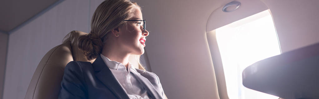 attractive businesswoman looking at window in plane during business trip - 写真・画像