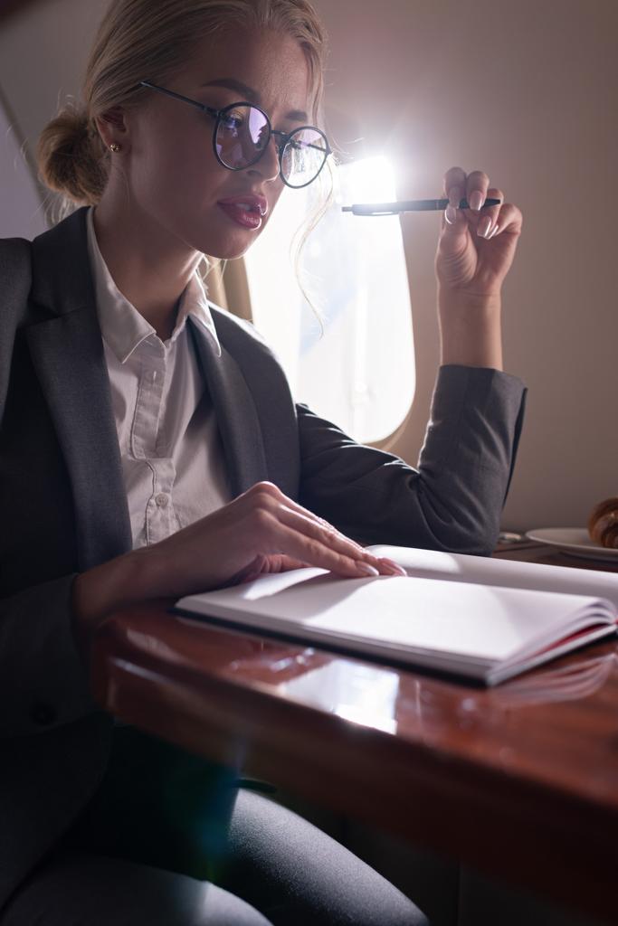 attractive businesswoman working with documents in plane during business trip - Photo, Image