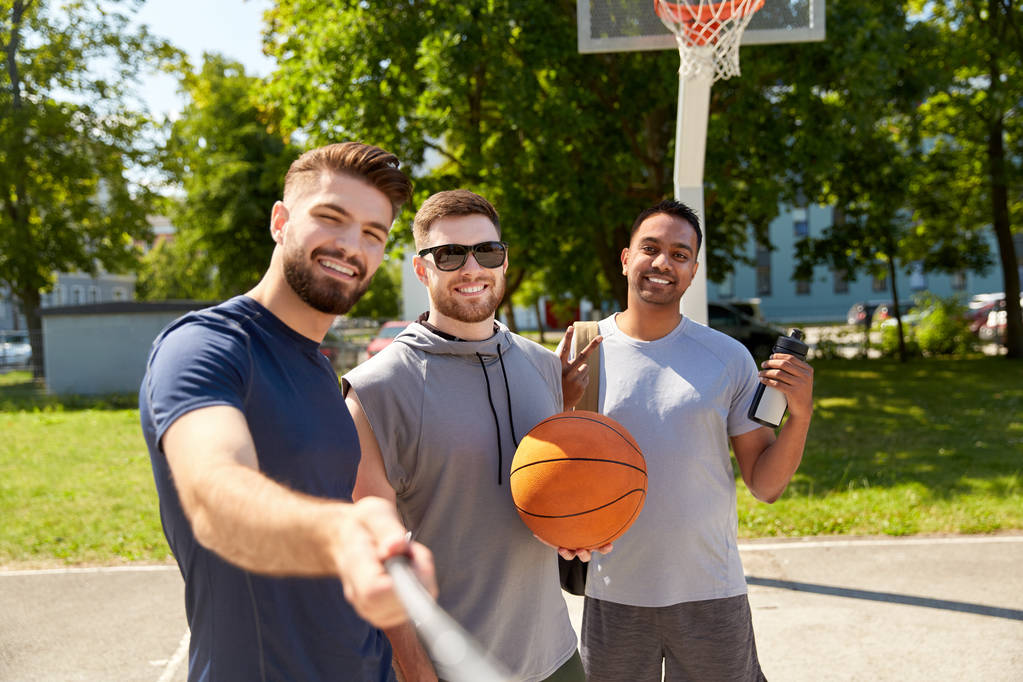 hommes heureux prenant selfie sur terrain de basket-ball - Photo, image