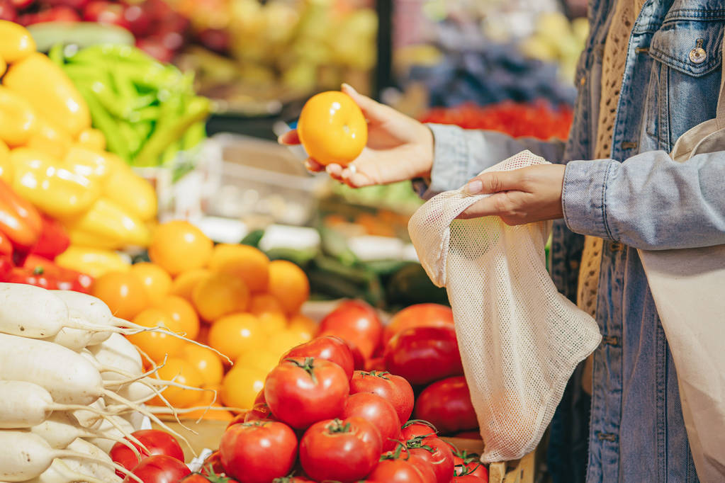 Las manos femeninas ponen frutas y verduras en bolsas de algodón en el mercado de alimentos. Bolsa ecológica reutilizable para ir de compras. Estilo de vida sostenible. Concepto ecológico
.  - Foto, imagen