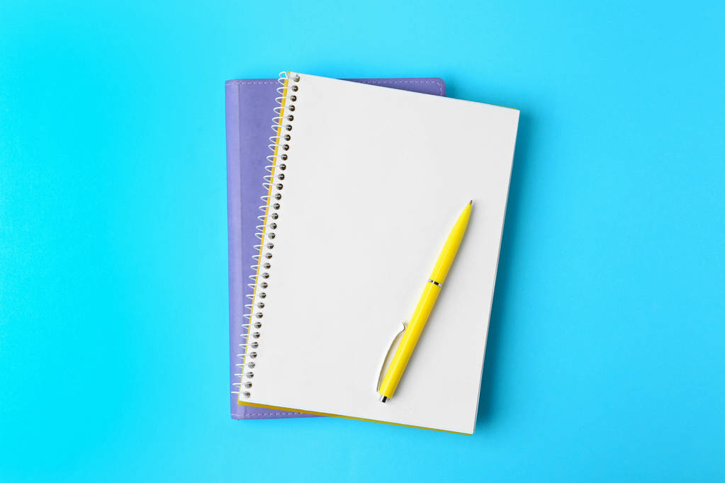 Notizbücher und Stift auf hellblauem Hintergrund, Draufsicht - Foto, Bild