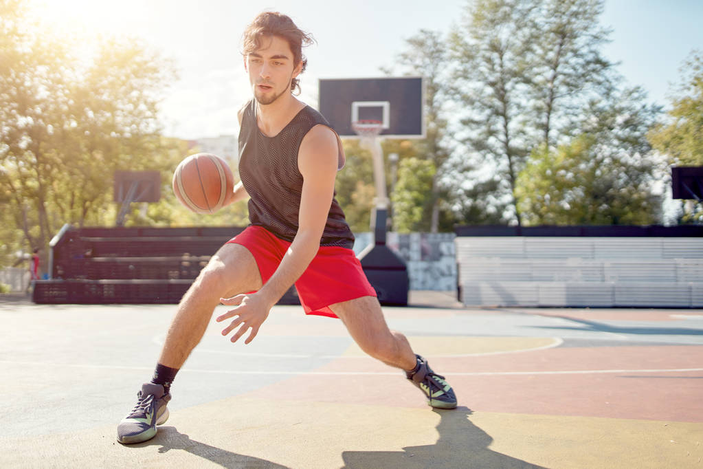 Foto de atleta en camiseta azul jugando baloncesto en el patio de recreo
 - Foto, imagen