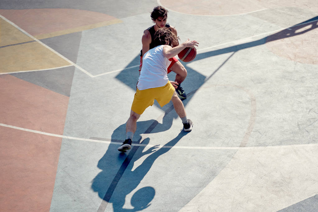 午前中に遊び場でバスケットボールをしている2人の選手のトップビュー. - 写真・画像