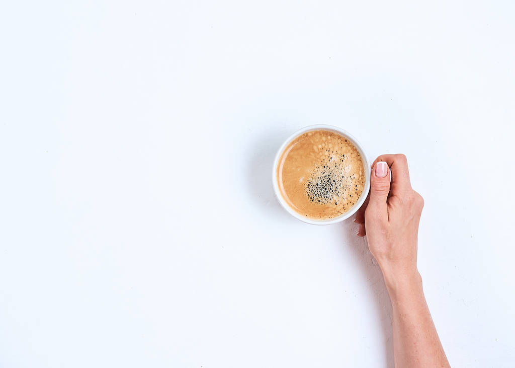 beyaz arka plan üzerinde kahve fincanı tutan kız eli, düz yatıyordu, üst görünümü - Fotoğraf, Görsel