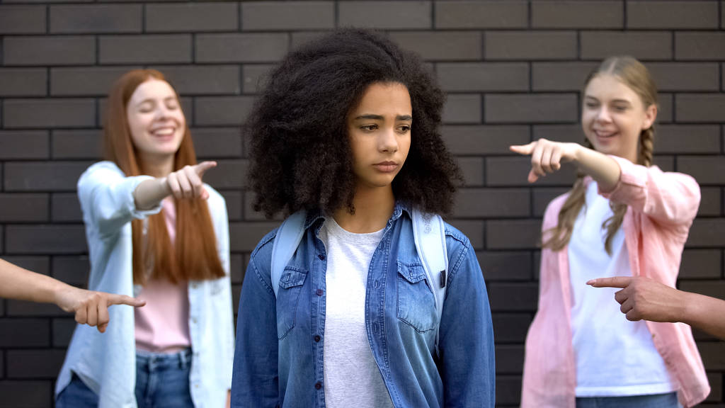 Cruel group of teens pointing fingers at curly afro-american schoolgirl, racism - Photo, Image