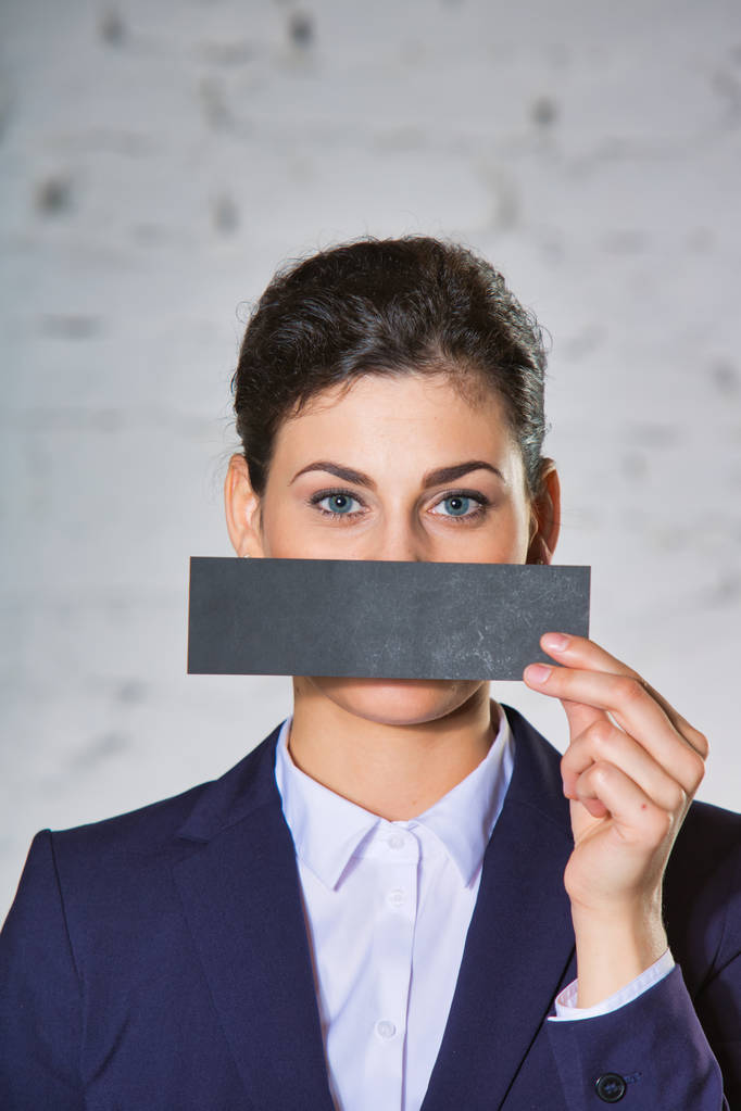 Giovane donna d'affari che copre la bocca con carta contro il muro di mattoni bianchi in ufficio
 - Foto, immagini