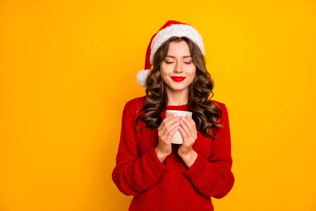 Szép hölgy gazdaság forró italt a kezében a legjobb reggelt kopás kötött pulóver és Santa hat elkülönített sárga háttér - Fotó, kép