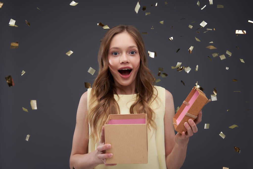 Feliz e espantado adolescente menina segurando caixa de presente aberta
 - Foto, Imagem
