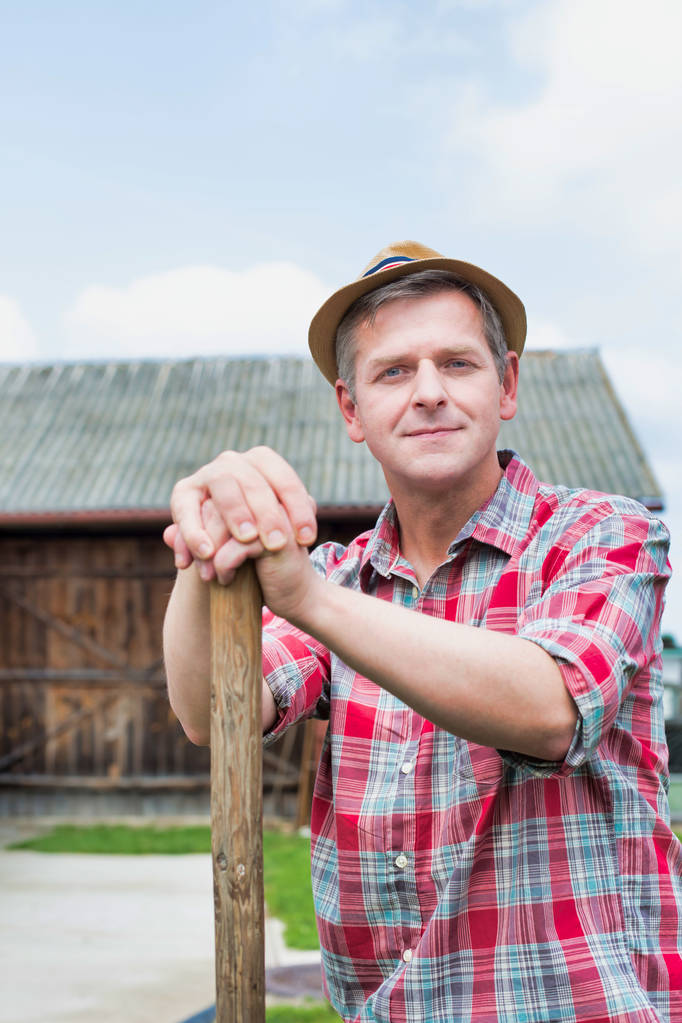 Thoughtful smiling farmer wearing hat at farm - Photo, Image