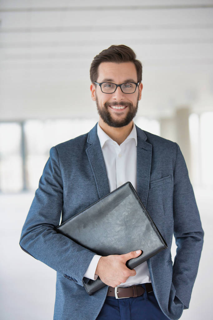 Porträt eines attraktiven Geschäftsmannes mit Brille und Mappe - Foto, Bild