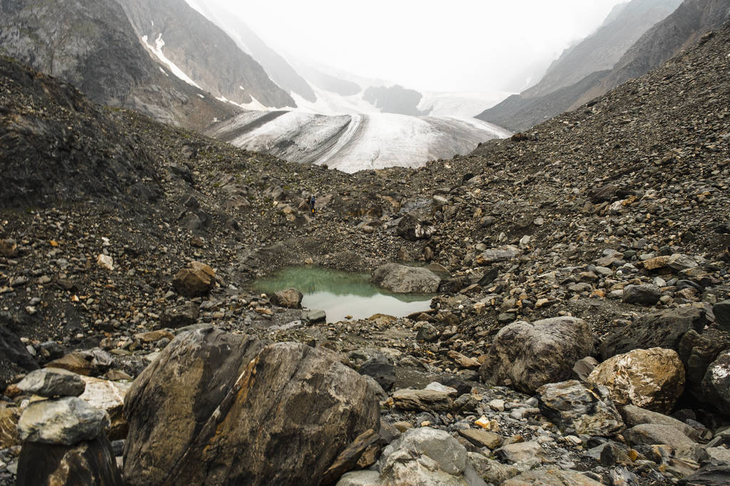 Ausläufer der Berge, kalter Gletscher. ein kleiner türkisfarbener Bergsee. Schöne Aussichten auf hohe schneebedeckte Berge und einen Gletscher bei einer Tour durch die Natur des Altai. Wandern und Bergsteigen in den Bergen - Foto, Bild