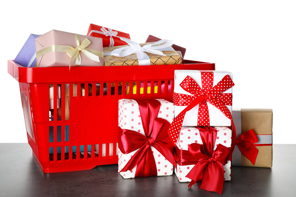 Bevásárlókosár különböző ajándékdobozokkal, szürke táblán fehér háttéren - Fotó, kép