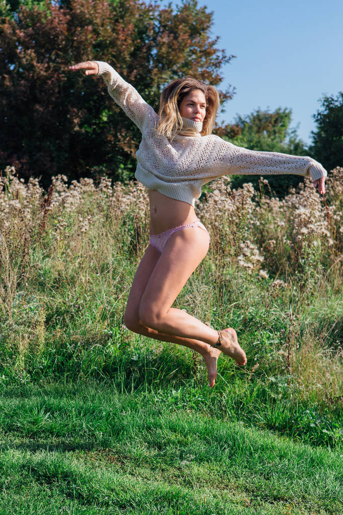 glückliche junge schöne Frau springt barfuß in ein grünes Feld - Foto, Bild