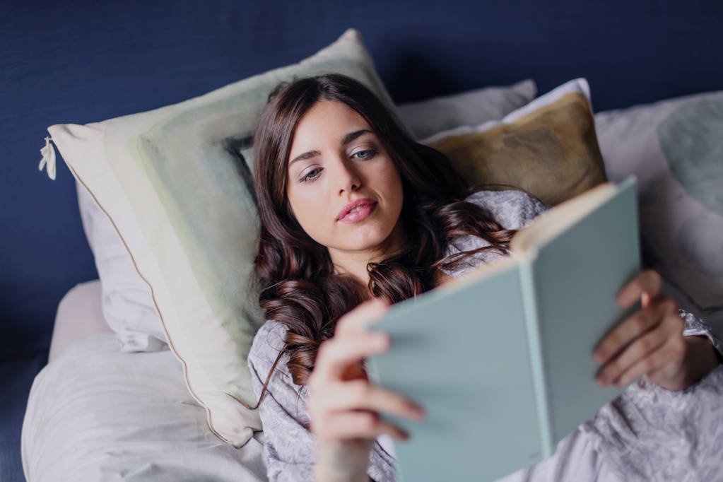 Tyttö lukee makaa sängyllä
 - Valokuva, kuva