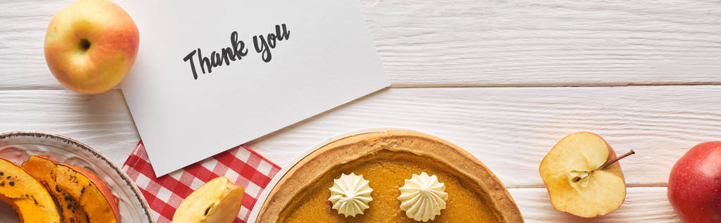 вид сверху на тыквенный пирог с благодарственной открыткой на деревянном белом столе с яблоками, панорамный снимок
 - Фото, изображение