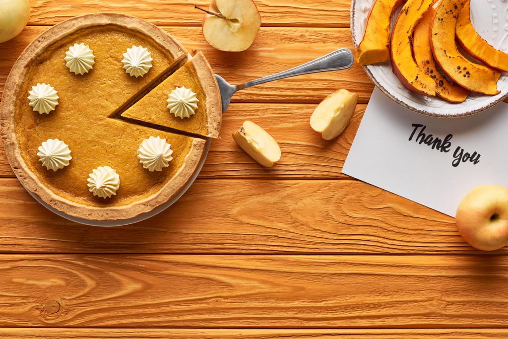 Top uitzicht van pompoen pie met dank u kaart op houten tafel met appels - Foto, afbeelding